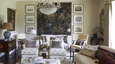 Traditional living room with tapestry on wall, antique paintings and printed armchairs