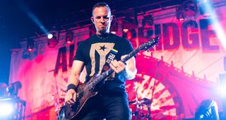 Mark Tremonti plays his PRS singlecut onstage with Alter Bridge against a pink and red background