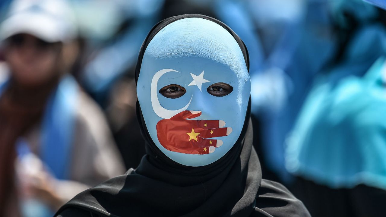 A demonstrator wears a mask showing solidarity with China&amp;#039;s Uighur population.