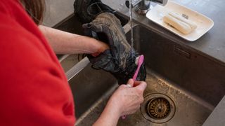 A woman cleaning hiking boots in the sink