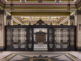 The two bronze screens with clocks that define the colourful and eclec- tically detailed Registration Hall. Note the far bronze doors to the Grand Temple