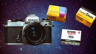 Nikon film camera and rolls of 35mm film in front of a starry backdrop taken with a film camera