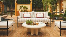 Patio with striped outdoor sofa in beige and white and circular stone coffee table
