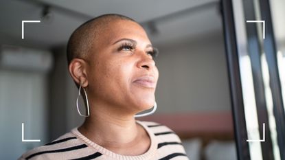 Woman looking out of window at home, experiencing symptoms of menopause and anxiety