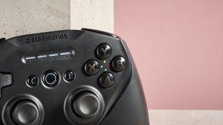 Close-up of face buttons on SteelSeries Stratus Duo, leaning on plinth with background