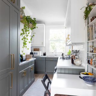 Grey and white galley kitchen with rug and small table