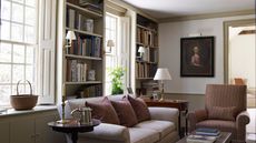 Traditional living room with sconces, large windows and sofa with bookshelves and antique painting