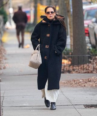 A photo of Katie Holmes pairing black ankle boots with ivory trousers.