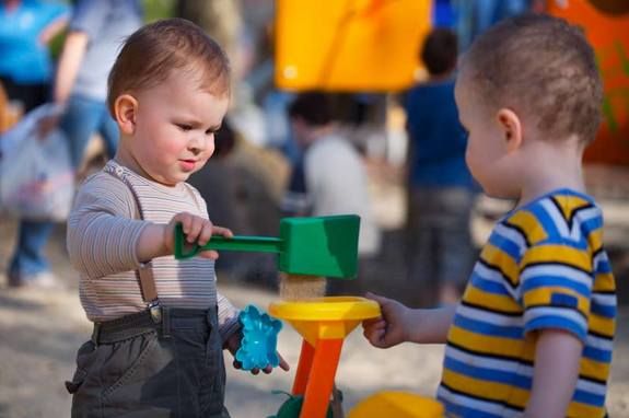 Two toddlers playing together on a playground.