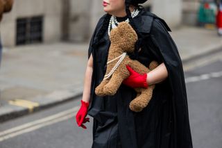 a woman at fashion week carrying a furry clutch by Simone Rocha