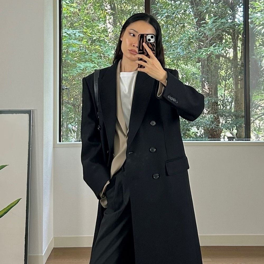 Woman wears white top, black coat, black tailored trousers