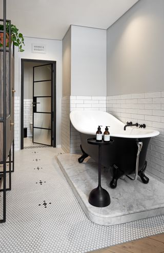 A monochrome bathroom idea with black freestanding bath and black framed doors
