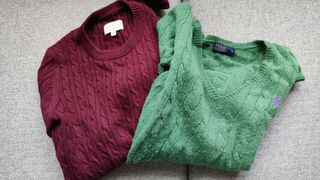 Image shows one burgundy and one green jumper folded up.