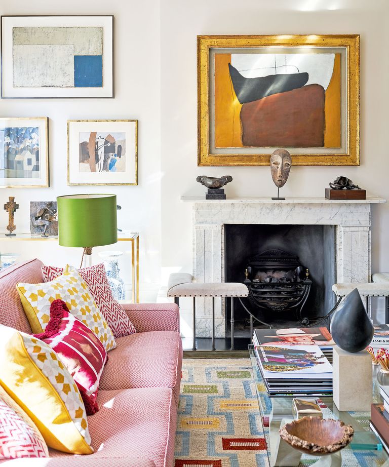 mixing patterns in a living room with pink sofa, patterned cushions, patterned rug and marble fireplace