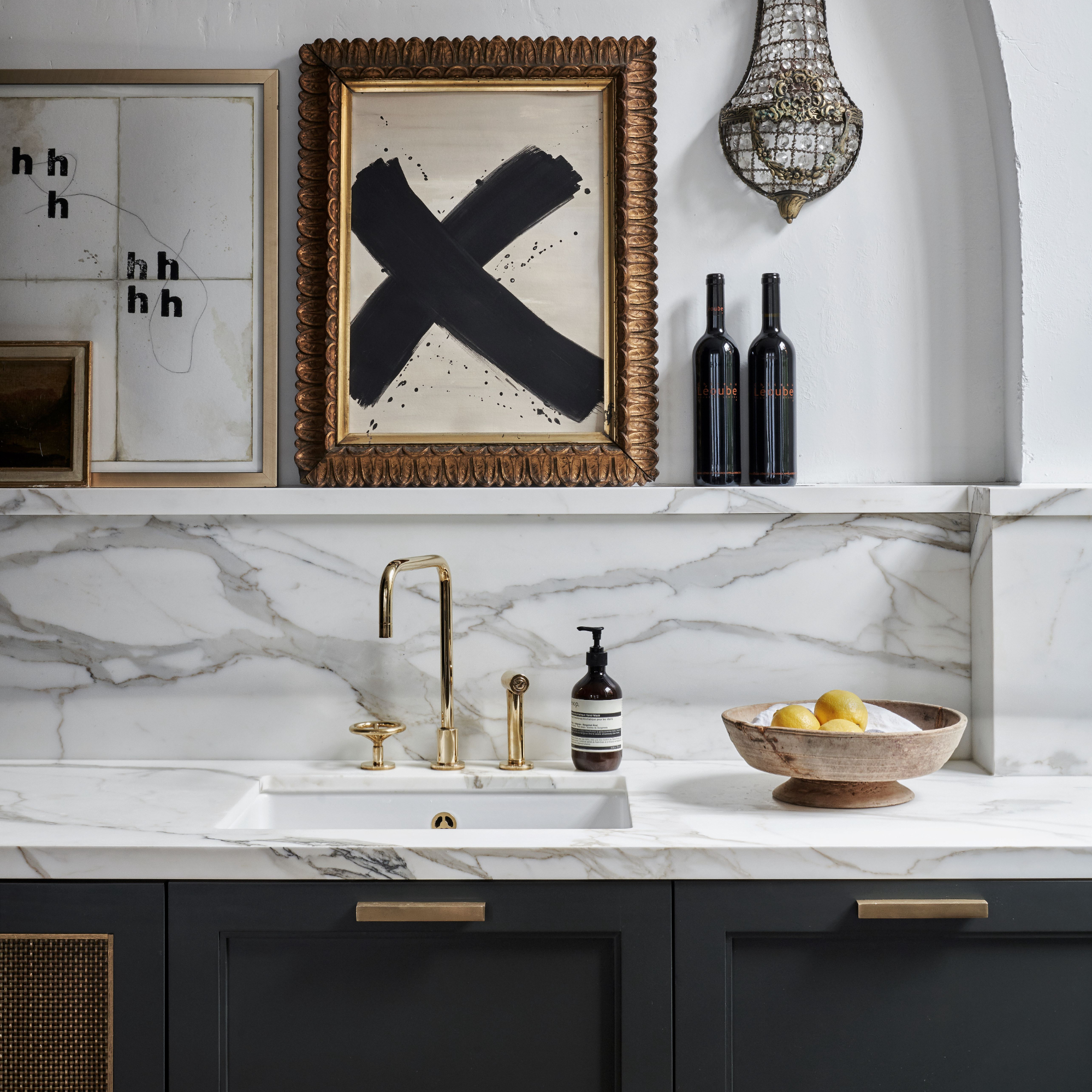 Kitchen detail with butler's sink with brass taps, marble worktop and splash-back and white walls