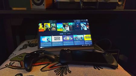 KYY Portable Monitor next to Steam Deck OLED and controller on blanket with cosy lighting.