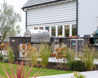 outdoor kitchen with ornamental grasses as divider designed by Consilium Hortus
