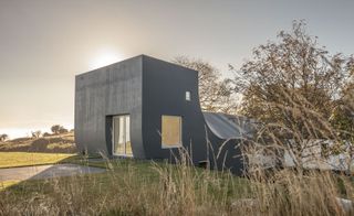 Grey coloured cottage with white frame door and window