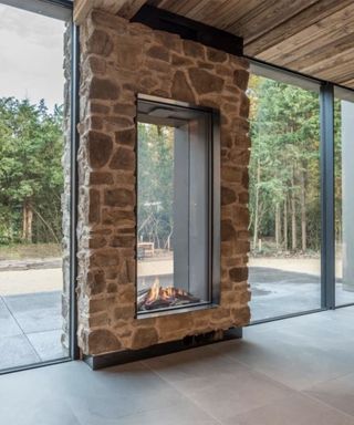 A fireplace built between see through glass on an exterior wall so it can be enjoyed inside and out