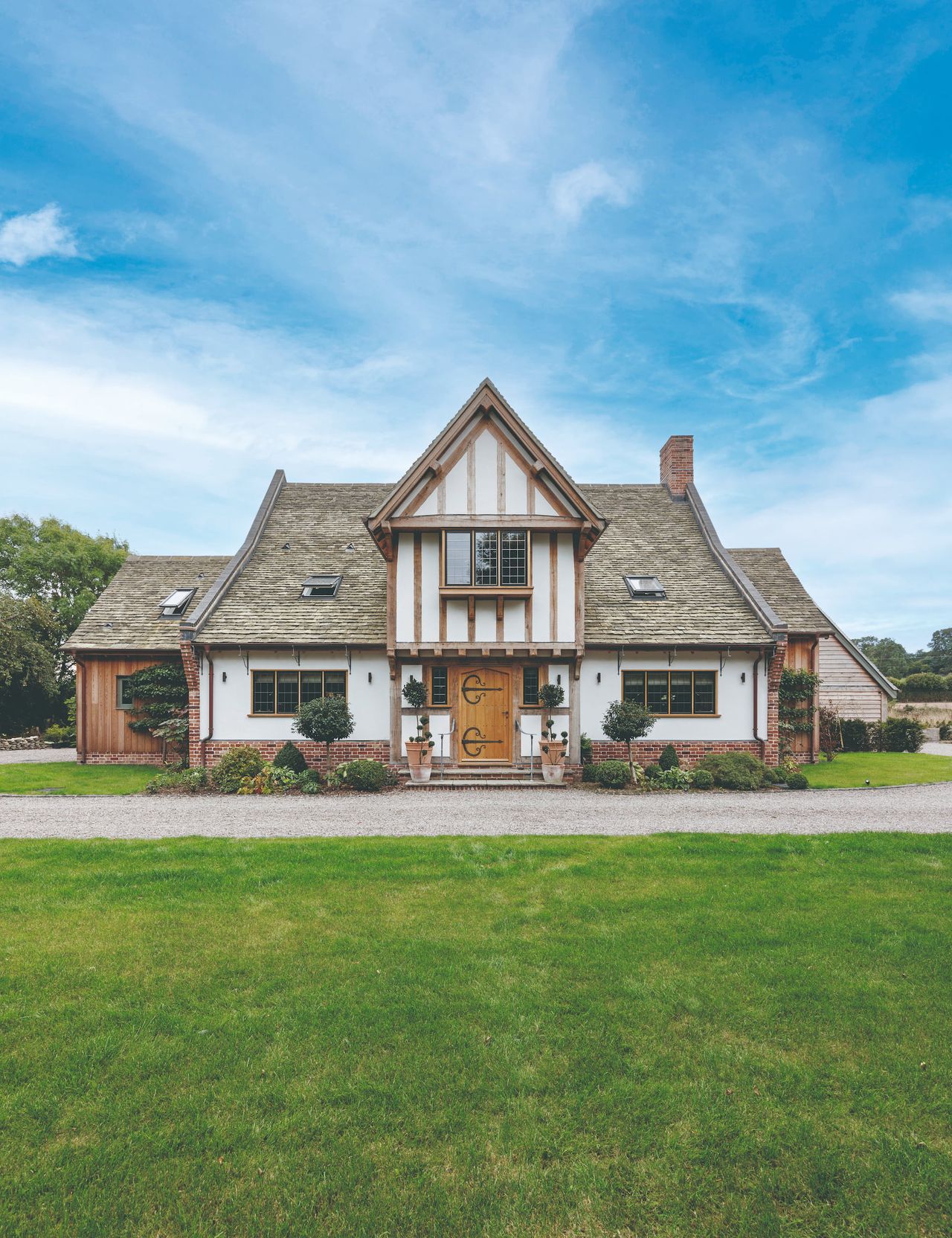 An oak framed home with a green lawn and blue skies