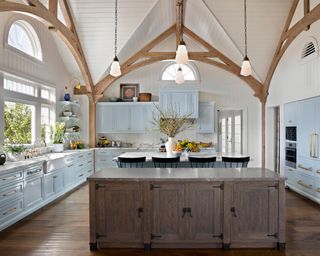 kitchen with beamed, shiplap ceiling, blue cabinets and island, black barstools and washed wooden island