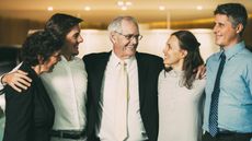 Smiling senior business man embracing family