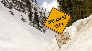 An avalanche warning sign buried in deep snow
