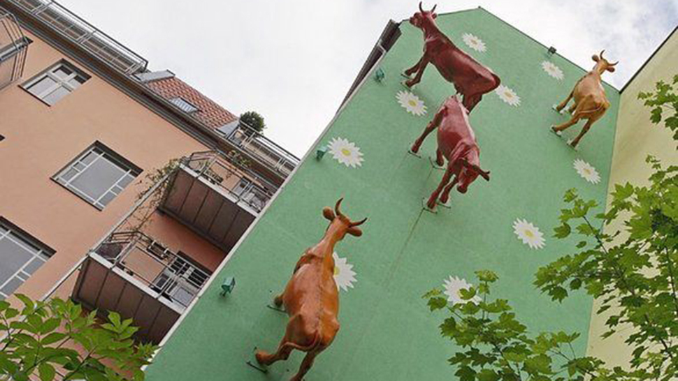 The Return of the Cows sculptures climbing a housing block