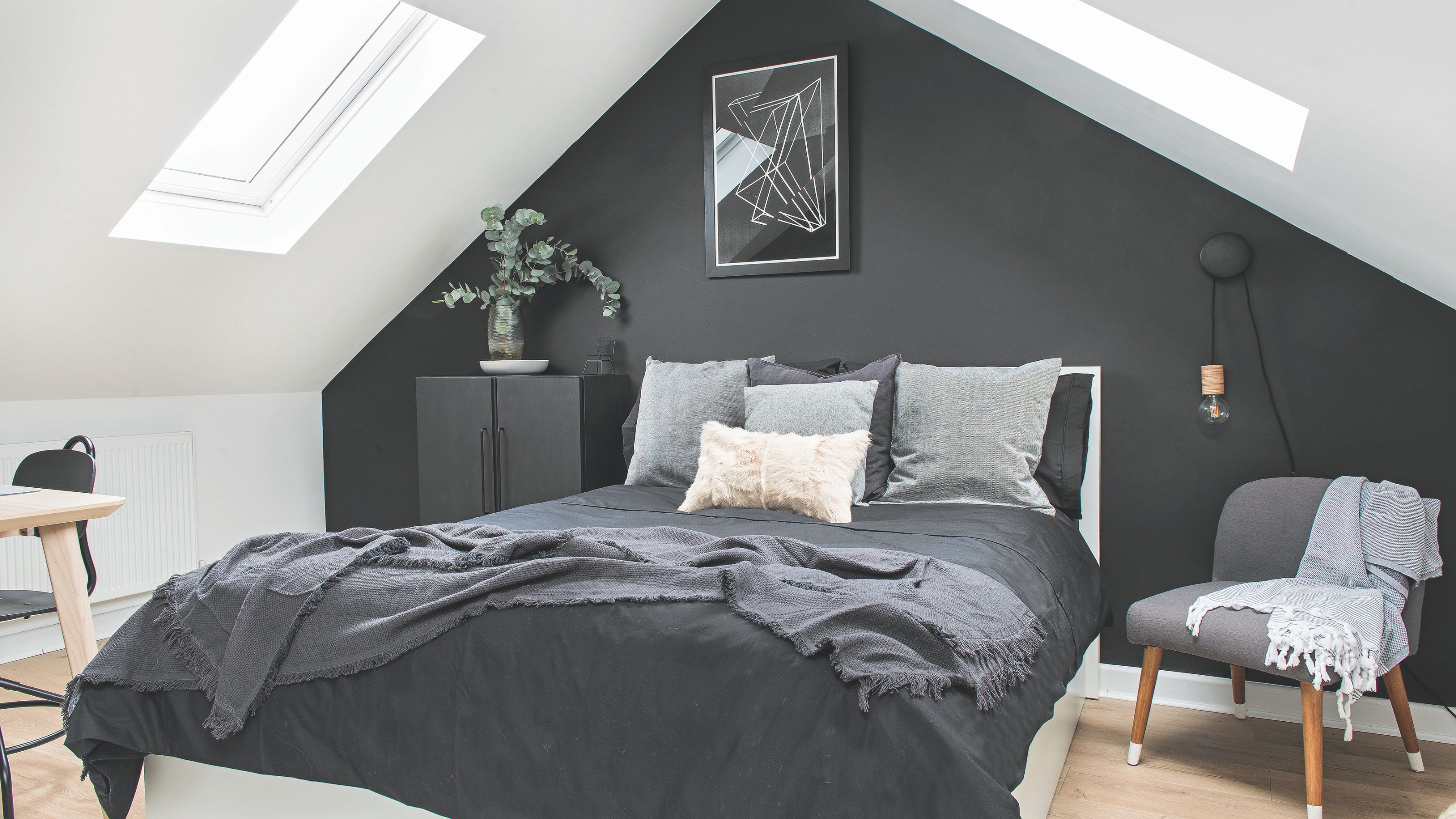 Master bedroom in converted loft, with a monochrome colour scheme, black feature wall and rooflights to bring in light