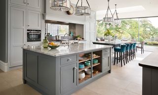 A large open plan kitchen picture with gray cabinetry, pendant lighting and glass sliding doors.