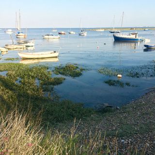 seaside view with white and blue boats and shore with stones and pebbles