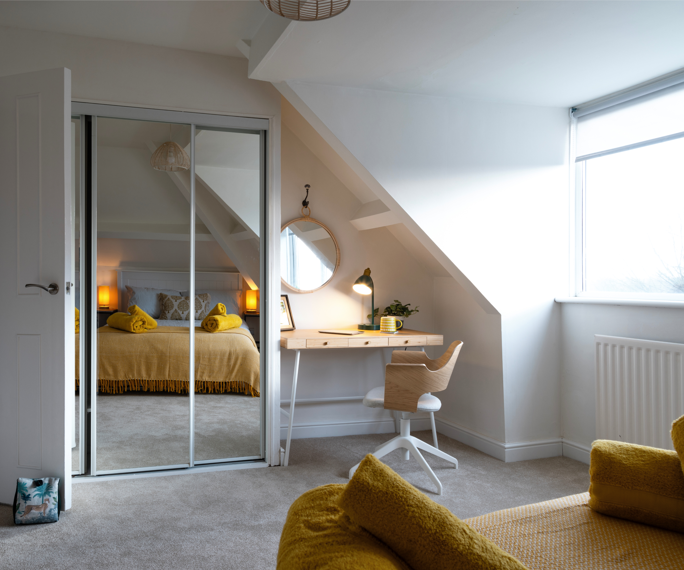 mirrored wardrobes and desk in sloped area leading towards alcove window