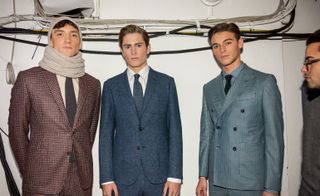 Three models stood next to each other with one wearing woven suits