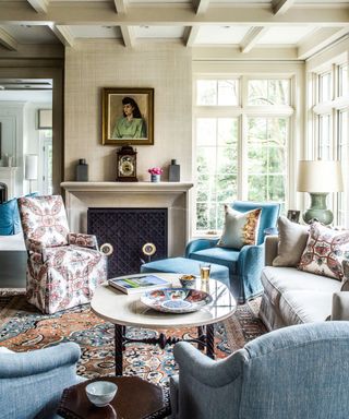 A living room with vaulted ceilings, a fireplace, blue and white seating and a vintage rug