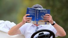 golf referee in a buggy reading the rules of golf