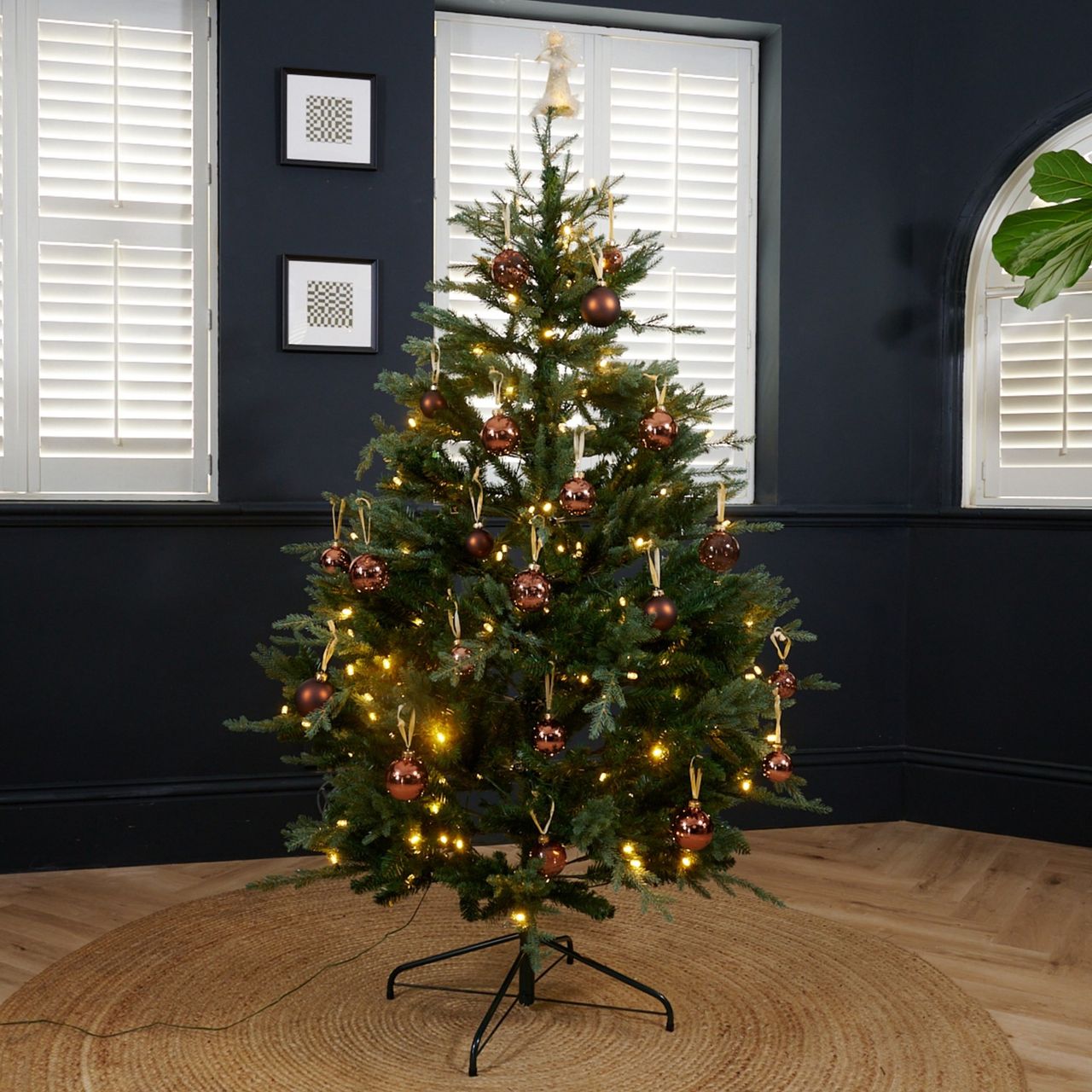 Habitat's 6ft Pre lit Upswept Mixed Tip Christmas Tree decorated with Cox &amp; Cox's brown shatterproof baubles set up in a black-painted living room