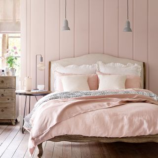 Pink bedroom with wall panelling, wooden bed and pendant lighting