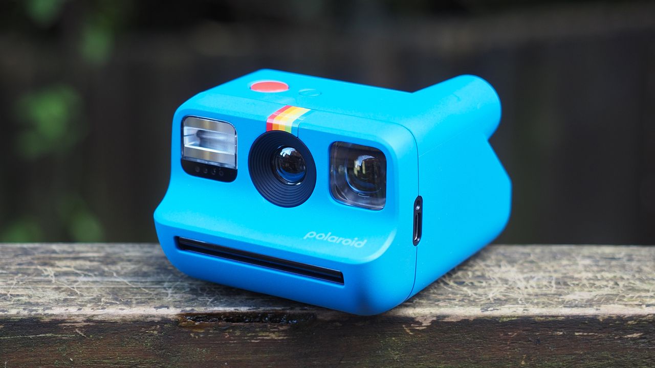 Blue Polaroid Go Gen 2 camera, on a wooden surface in a woodland setting