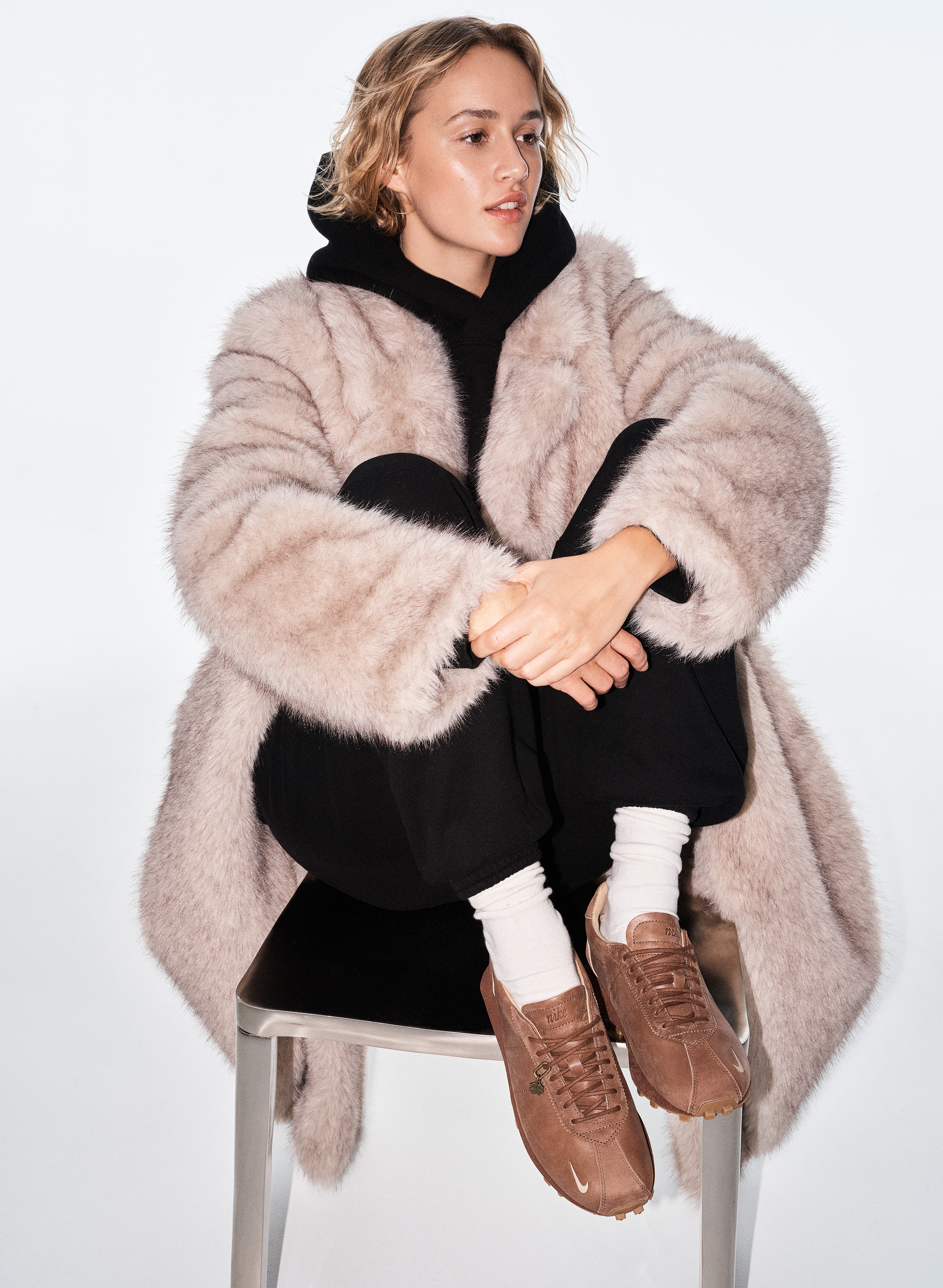 a model wears the Aritzia x Nike sneaker collaboration with a fur coat and sweatsuit
