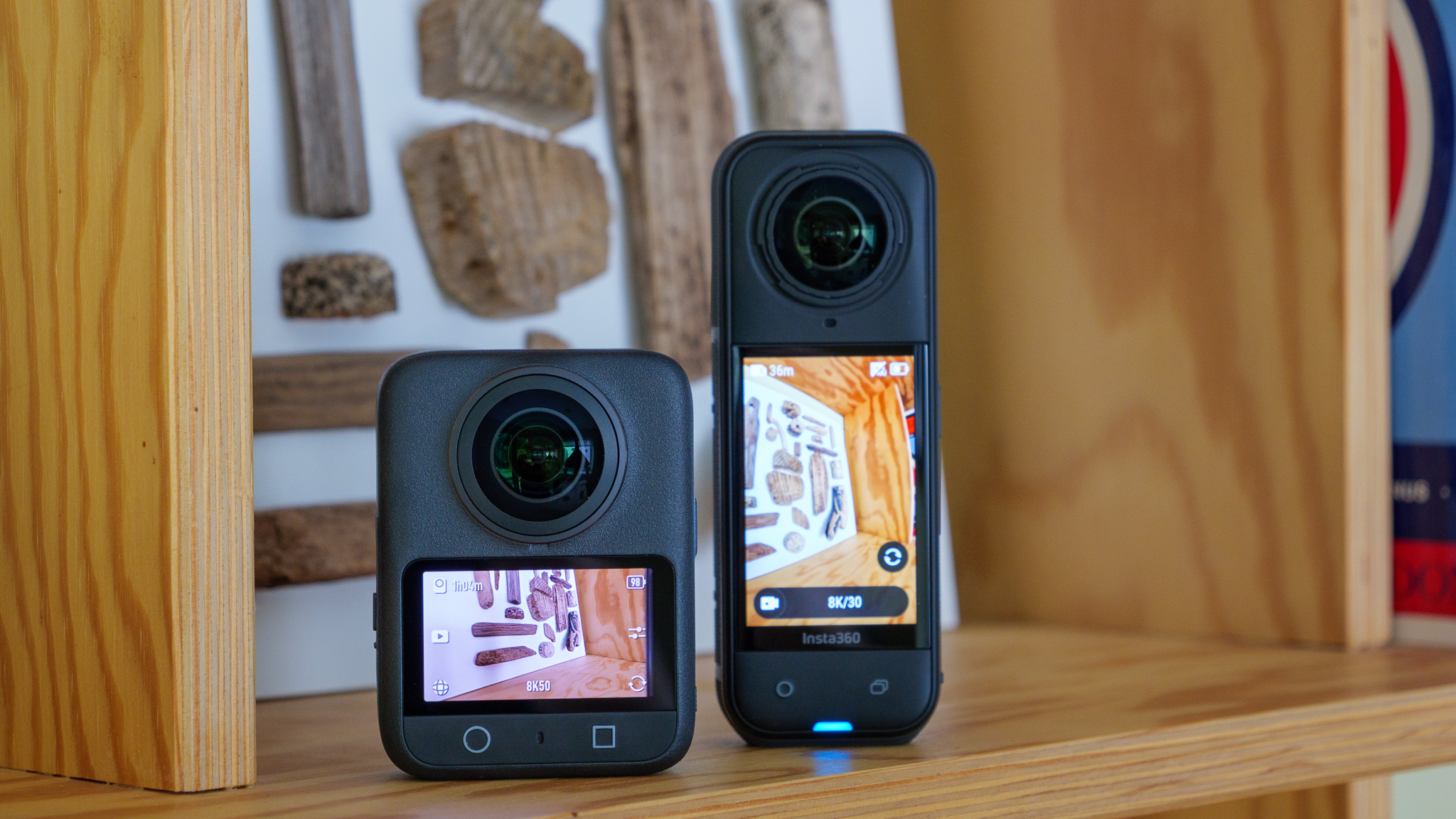 DJI Osmo 360 and Insta360 X5 cameras on wooden shelf