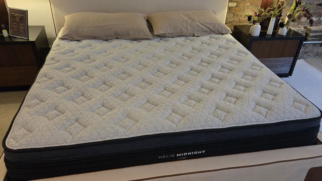 New Helix Midnight Luxe mattress on a white platform bed frame with headboard, shot from a slight angle