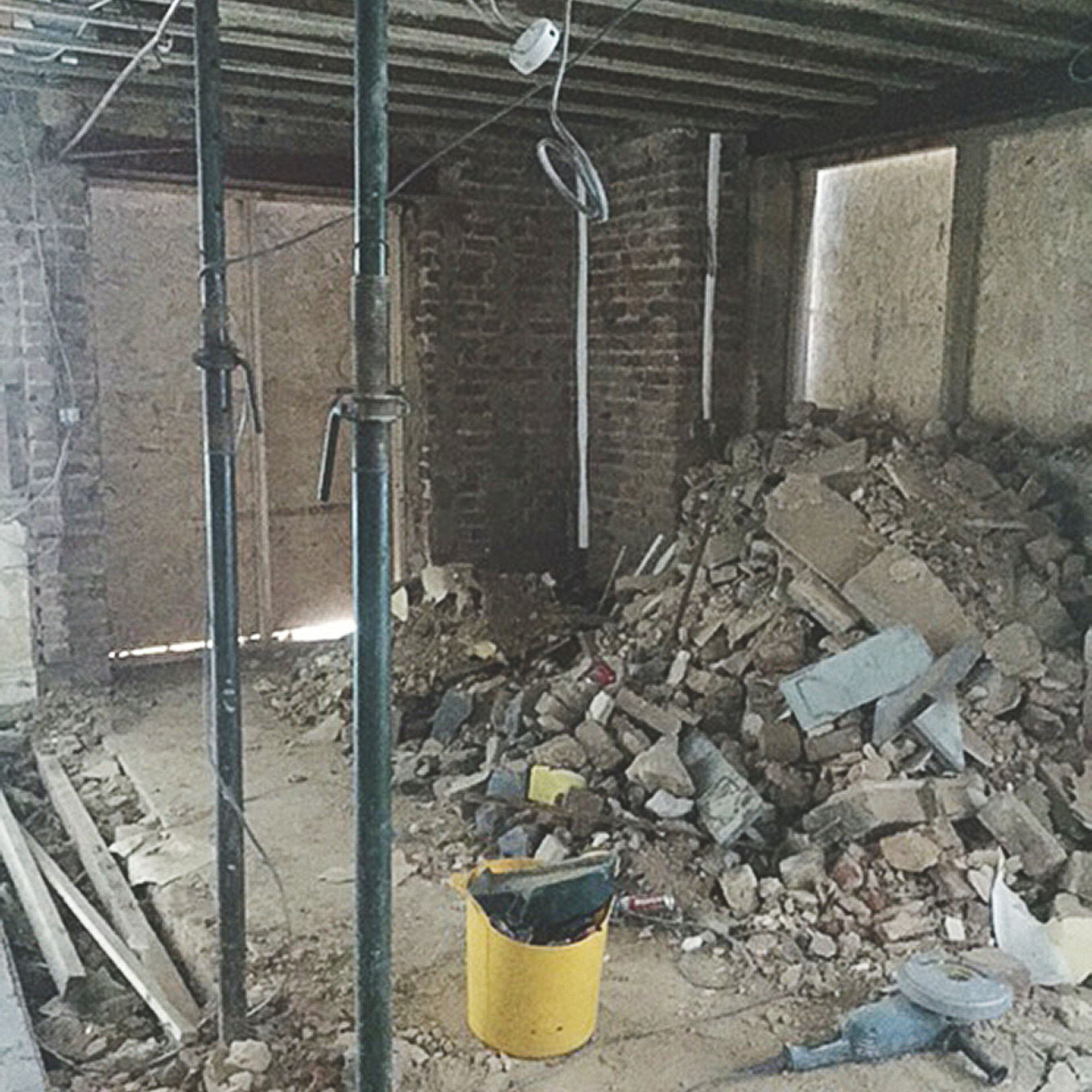 Process of converting a basement, with piles of rubble and acrow props supporting the ceiling