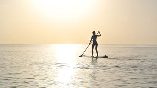 Stand up paddleboarding: a woman practising SUP on the ocean