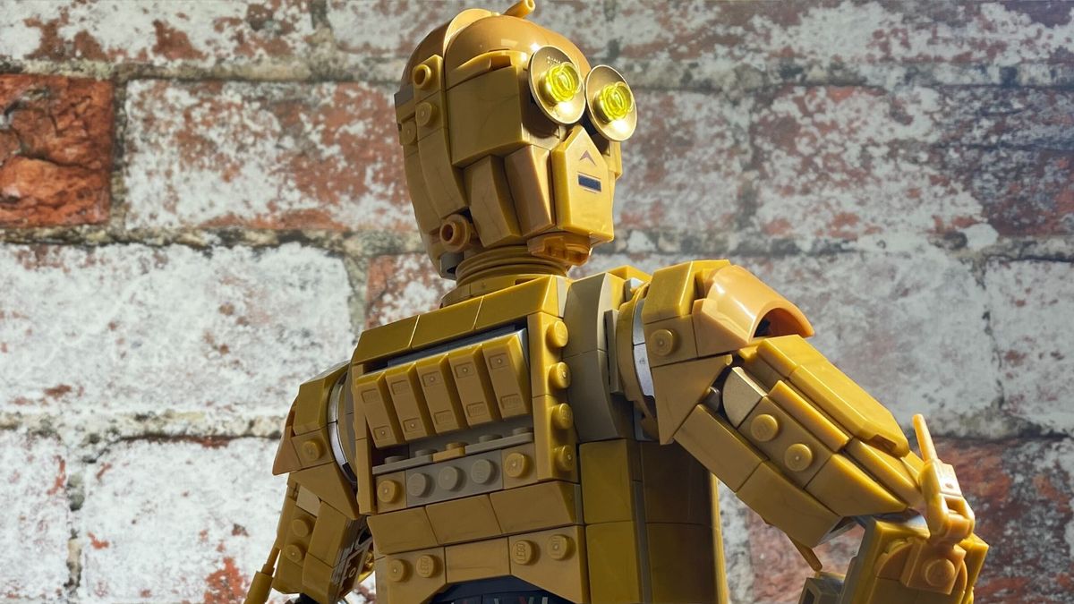 Lego C-3PO against a brick wall, looking off to one side