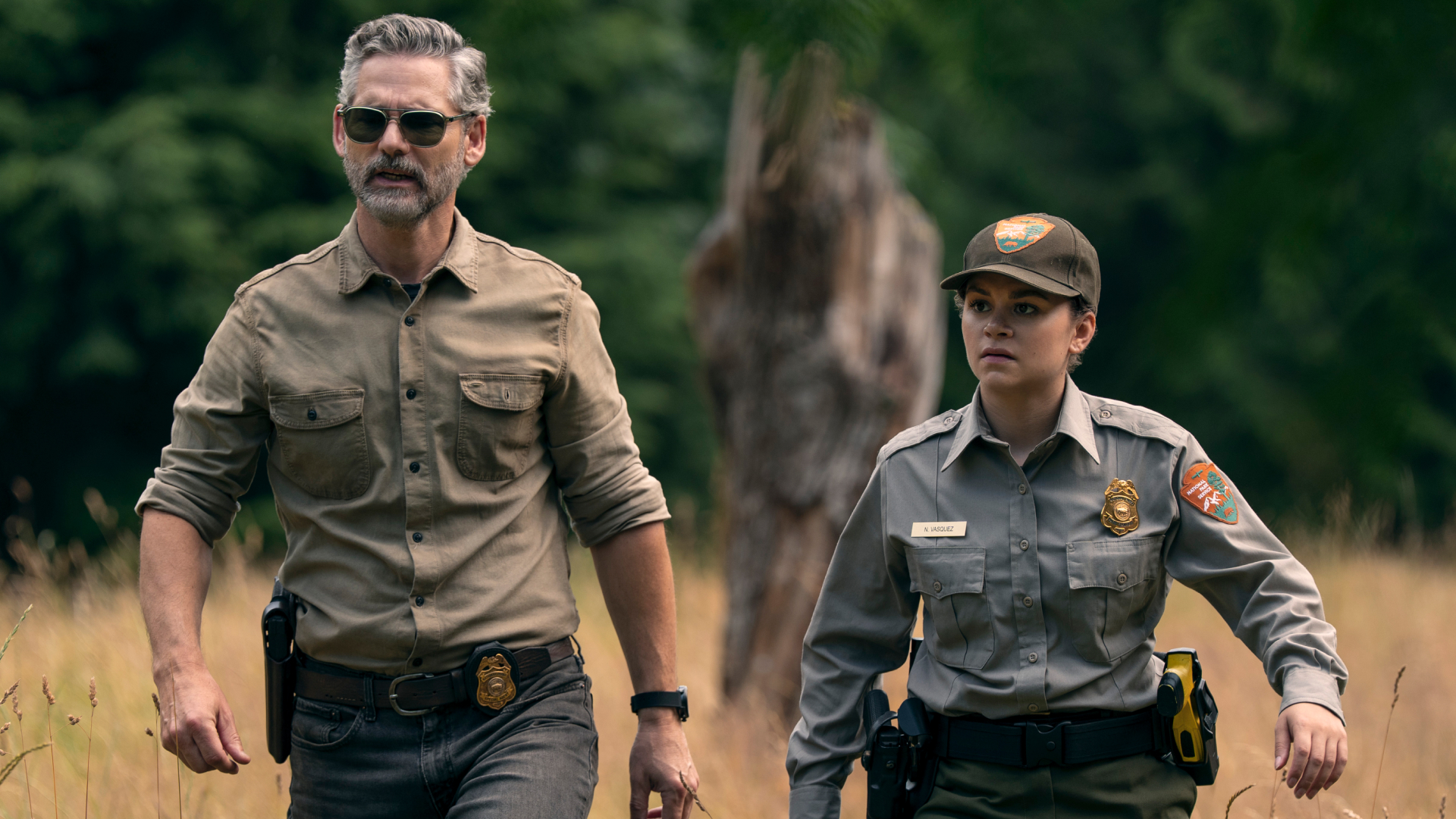eric bana and Lily Santiago as park ranger officers walking through a field in untamed