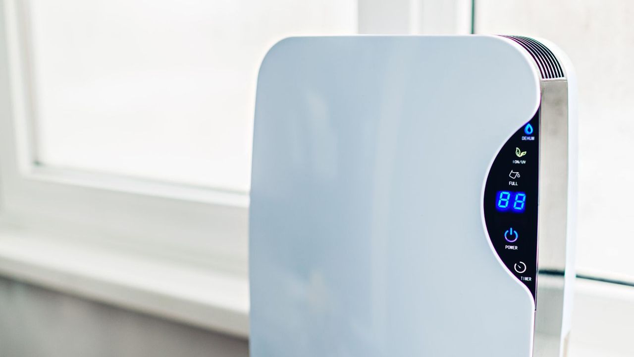 A white dehumidifier with a blue LED control pannel