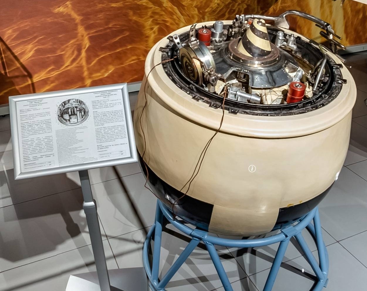 A metal ball sits on a metal stand next to a plaque