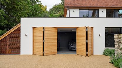 Urban Front craft beautiful bifold garage doors using natural hardwood - for a luxury but practical contemporary style statement. Parma design, double bi-fold. European oak w 5400mm x h 2400 on a white garage 