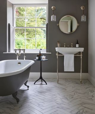 Gray bathroom with gunmetal gray walls and matching tub, marble style flooring, white basin, chrome fixtures and fitti