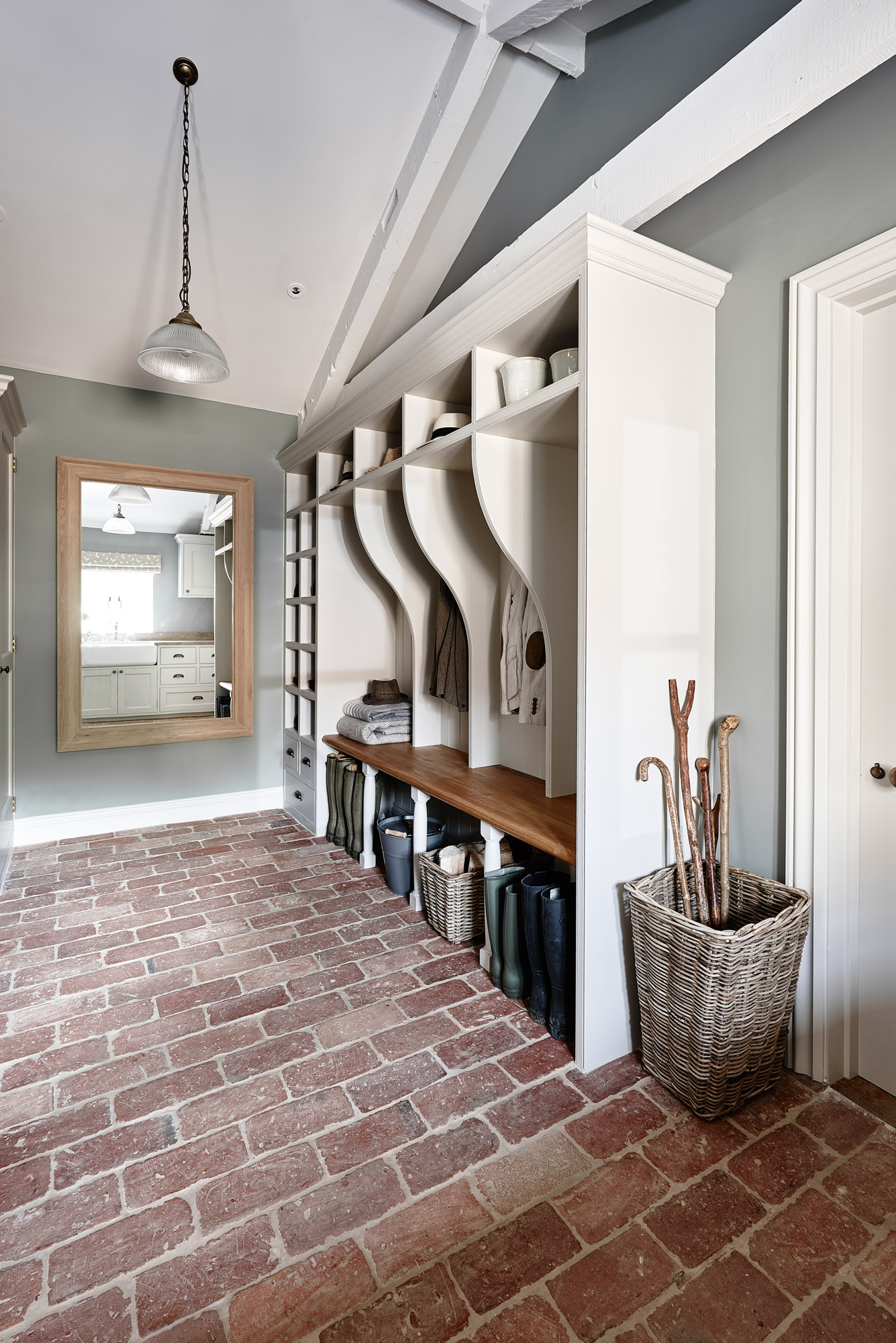 Mudroom with brick floor tile, grey walls and white cabinetry